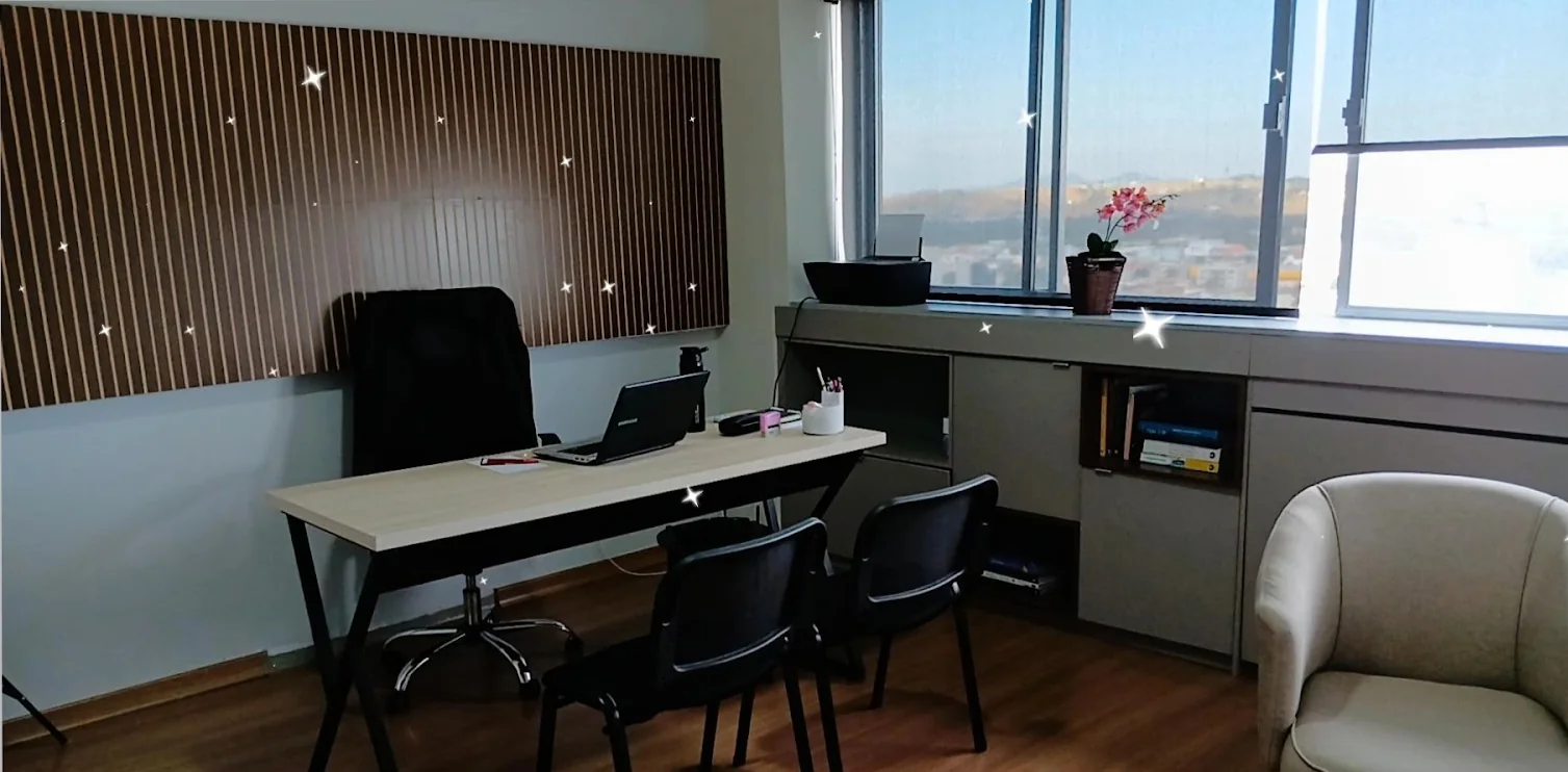 Consultório com mesa de atendimento, cadeiras e janela ampla